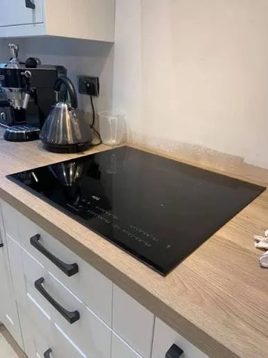 AEG black glass induction hob fitted into light wood-effect worktop