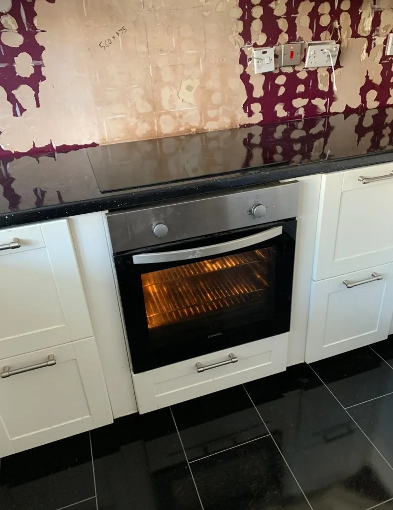 Black glass hob installed above Lamona oven with white shaker cabinets