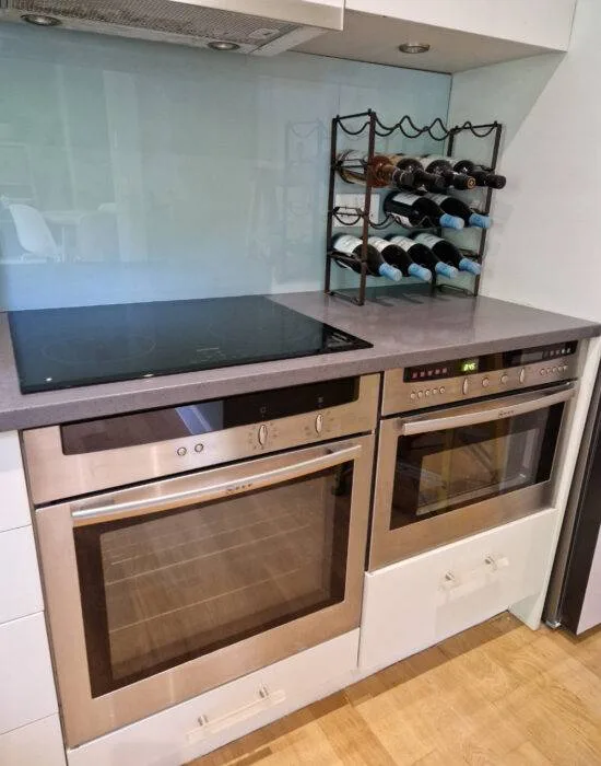 Black induction hob with Neff built-in ovens and glass splashback
